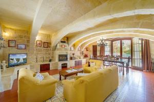 克伦蒂Ta' Majsi Holiday Home的客厅设有黄色家具和石墙