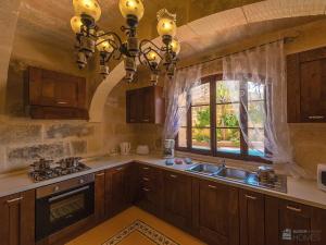克伦蒂Ta' Majsi Holiday Home的厨房配有木制橱柜、水槽和窗户。