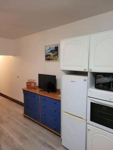 卡文Murray's Lodge: Self-Catering Accommodation.的带白色家电的厨房和带电视的书桌