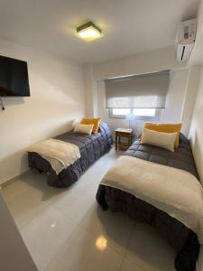 萨尔塔HAUS APARTAMENTOS的一间卧室设有两张床,墙上配有电视。