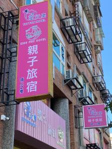 罗东镇童玩樂親子旅宿Toy Fun Hotel的建筑物一侧的粉红色标志