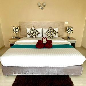 华欣瑟普莱城市酒店的一间卧室配有一张大床,上面有两朵红玫瑰