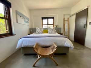 普利登堡湾Stay On Main Plett - Contemporary 2-Bedroom Apartment的一间卧室配有一张大床和一张木椅