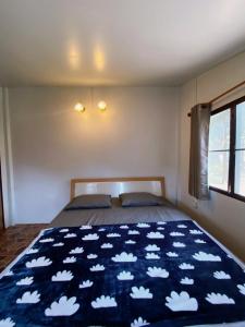 王南安科บ้านสวนจันทร์เจ้า的一间卧室配有一张带蓝色毯子和云层的床
