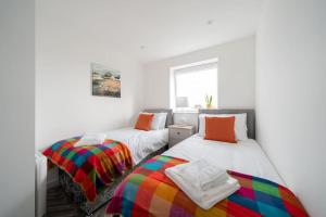 阿伯丁Links Loft -2 bed apartment minutes from Aberdeen beach的白色墙壁客房的两张床