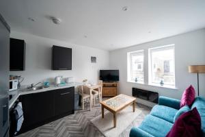 阿伯丁Links Loft -2 bed apartment minutes from Aberdeen beach的一间带蓝色沙发的客厅和一间厨房