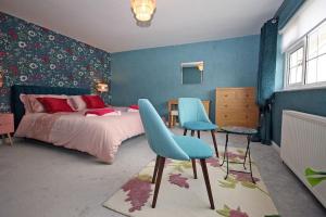 卡纳芬Rhoslan. Boutique style farmhouse in Snowdonia的一间卧室配有一张床和两张蓝色椅子