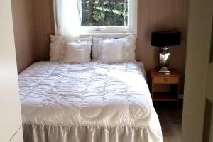 赫讷福斯peaceful place的一张带白色床单和枕头的床,靠窗