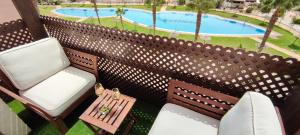 雷塔马尔Ático de ensueño, El Toyo, Almería - Playas, Golf, Cabo de Gata的一个带两把椅子和一张桌子的阳台以及一个游泳池