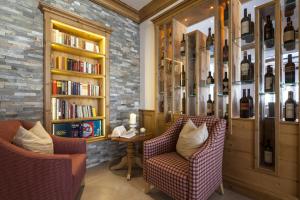 上陶恩Superior Hotel Panorama的图书馆配有两把椅子和一张桌子,备有书籍