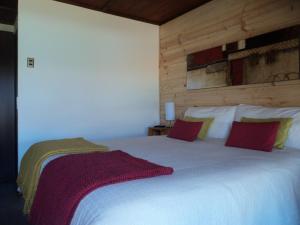 圣佩德罗·德·阿塔卡马Hoteles Pueblo de Tierra的卧室配有带红色枕头的大型白色床