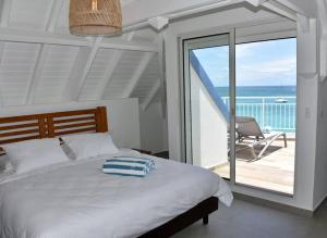 圣马丁岛Walee Beach Penthouse by the sea, 2 bedrooms, pool的一间卧室配有一张床,阳台配有椅子
