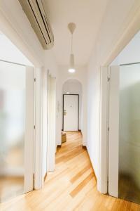 米兰Sebino Guest House的一条空的走廊,公寓拥有白色的墙壁和木地板