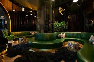 达拉斯Virgin Hotels Dallas的客厅配有绿色沙发和凳子