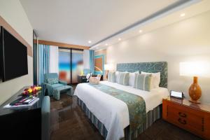 坎昆The Pyramid Cancun by Oasis - All Inclusive的酒店客房带一张大床和一把椅子