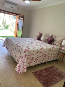 皮拉西卡巴Espacin Maricris-28 min. Thermas Sao Pedro的一间卧室配有一张带粉红色花卉床罩的床。