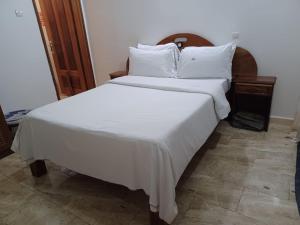 MboroLa Mboroise的一张配有白色床单和枕头的大床