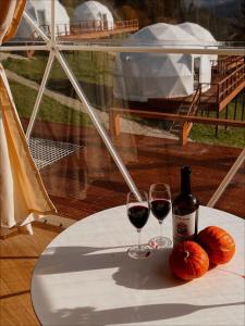 沃罗赫塔Глемпінг Де Вайб (devibe-vorokhta)的一张桌子,上面放着两杯红葡萄酒和南瓜