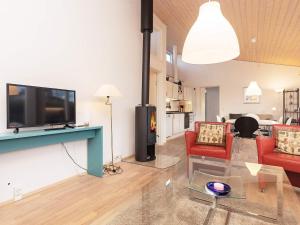 博恩瑟6 person holiday home in Bogense的客厅配有平面电视和红色椅子。