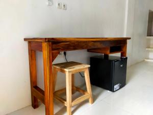 龙目岛库塔Mango Room Mandalika的一张木桌,旁边是一台电脑,旁边是凳子