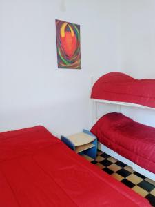 蒂尔卡拉Casa de Barro Tilcara的一间卧室配有两张红色床罩和一张桌子