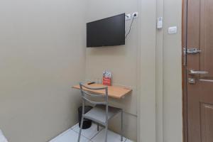 泗水RedDoorz near BG Junction Surabaya的客房设有书桌和墙上的电视。