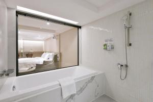 台中市春树商旅的一间带镜子和浴缸的浴室以及一张床