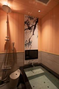 东京HOTELみなと-MINATO-的带淋浴的浴室和墙上的电视