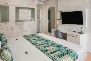 大加那利岛拉斯帕尔马斯Hotel Aloe Canteras的配有一张床和一台平面电视的酒店客房