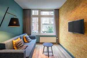 阿姆斯特丹Musea Hotel & Apartments的客厅配有沙发和墙上的电视