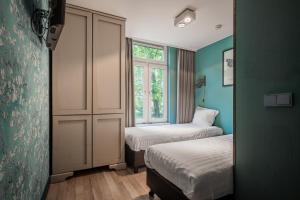 阿姆斯特丹Musea Hotel & Apartments的小房间设有两张床和窗户