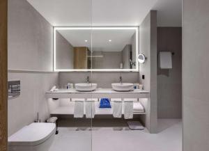 基辅Radisson Blu Hotel, Kyiv City Centre的浴室设有2个水槽、镜子和卫生间。