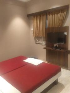 楠代德Ramakrishna International的一间设有红色床和电视的房间