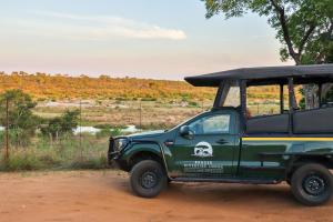 玛洛斯帕克Kruger Riverside Lodge - No Load-shedding的停在土路上的绿色吉普车