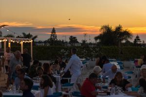 卡洛维诺里瓦滨海度假村 - CDS酒店的一群人坐在日落时分坐在桌子旁