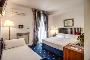 罗马拿破仑酒店的酒店客房设有两张床和一张桌子。