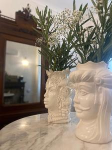 锡拉库扎Ortigia Twin Rooms的两个白头坐在桌子上,带花瓶