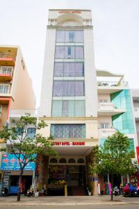 胡志明市LUXURY HOTEL HẬU GIANG的一座高大的白色建筑,有钟楼