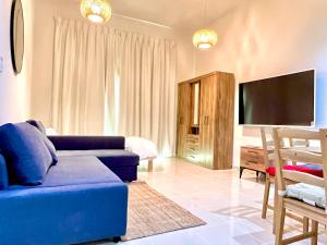 迪拜Calm&Cozy1BR- Dubai Silicon Oasis-15min-Dxb airpt的客厅配有蓝色的沙发和平面电视。