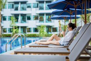 奥南海滩Holiday Style Ao Nang Beach Resort, Krabi的坐在游泳池旁的躺椅上的女人