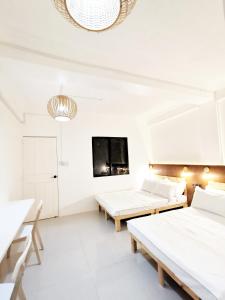 马尼拉NomadsMNL Hostel的白色的客房配有两张床和电视。