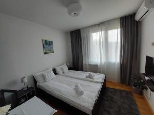 弗尔尼亚奇卡矿泉镇Vrnjci House的一间卧室配有一张带白色床单的床和一扇窗户。