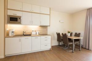 普劳西Hafendorf Haus 5 Apartment 2 Nr25的厨房配有白色橱柜和桌椅