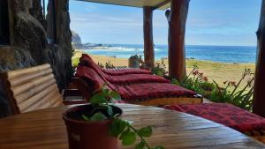 安加罗阿Cabañas & Hostal Tojika的海滩上带枕头和桌子的门廊