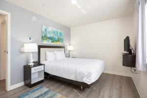 普利茅斯Waterwalk Minneapolis Plymouth的一间白色卧室,配有床和电视