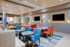 华盛顿堡Holiday Inn Express & Suites Ft. Washington - Philadelphia, an IHG Hotel的餐厅设有桌椅和平面电视。