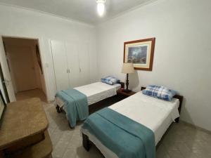 瓜鲁雅Guarujá praia das Pitangueiras a 50 metros do mar的酒店客房设有两张床和一张桌子。