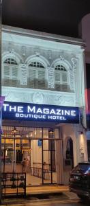 乔治市The Magazine Boutique Hotel的一座白色的大建筑,上面有蓝色的标志