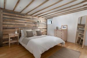 彭赞斯Cosy cottage, walk to Porthcurno beach, Pedn Vouder, Minack & PK Museum的卧室配有白色的床和木墙
