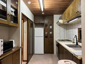 札幌LIT’S INN Sapporo的厨房配有白色冰箱和木制橱柜。